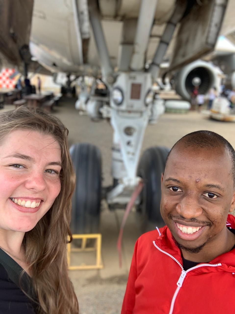 Njabulo and Uma smiling beneath an aircraft