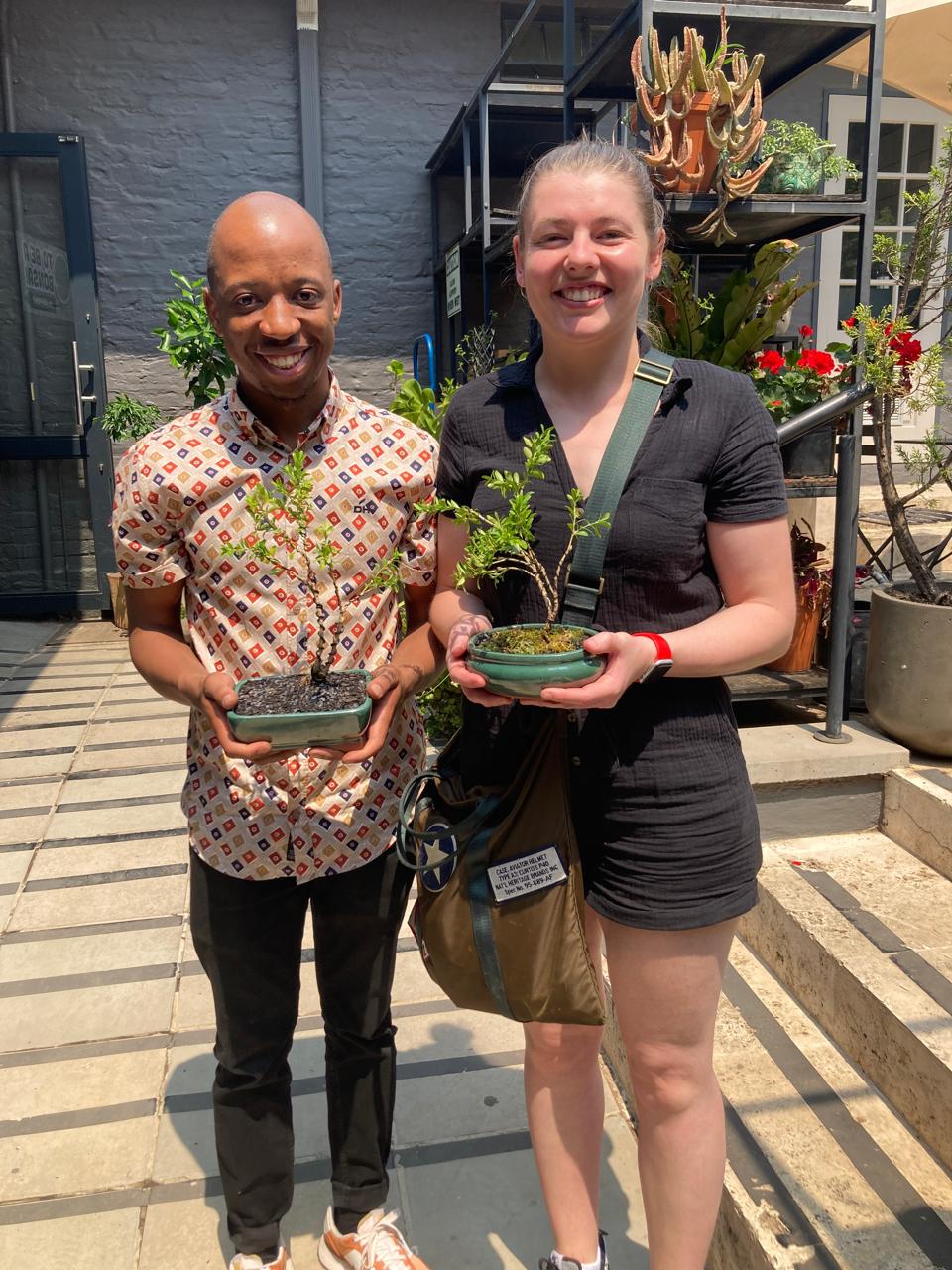 Njabulo and Uma holding bonsai trees