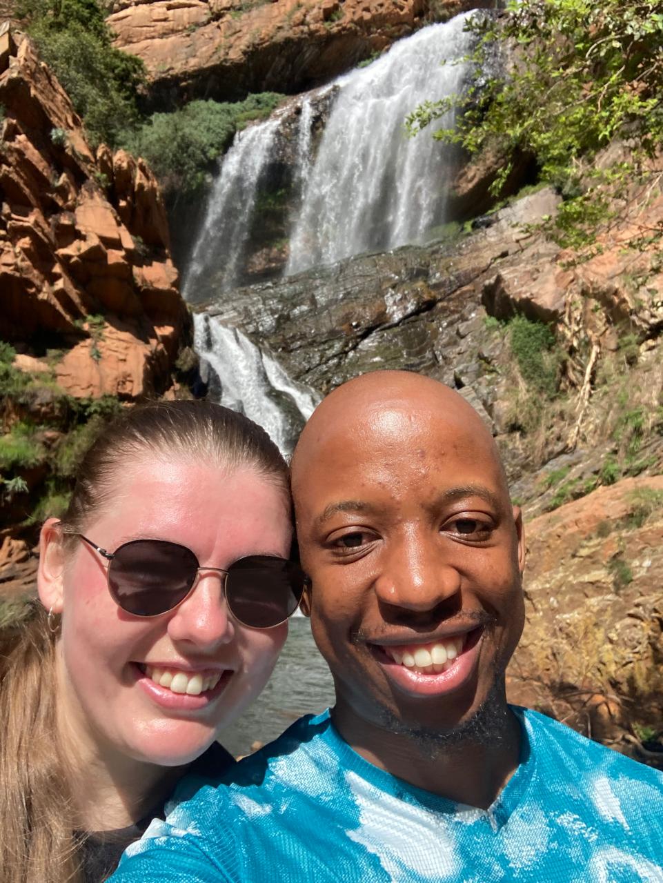Njabulo and Uma smiling in front of a waterfall